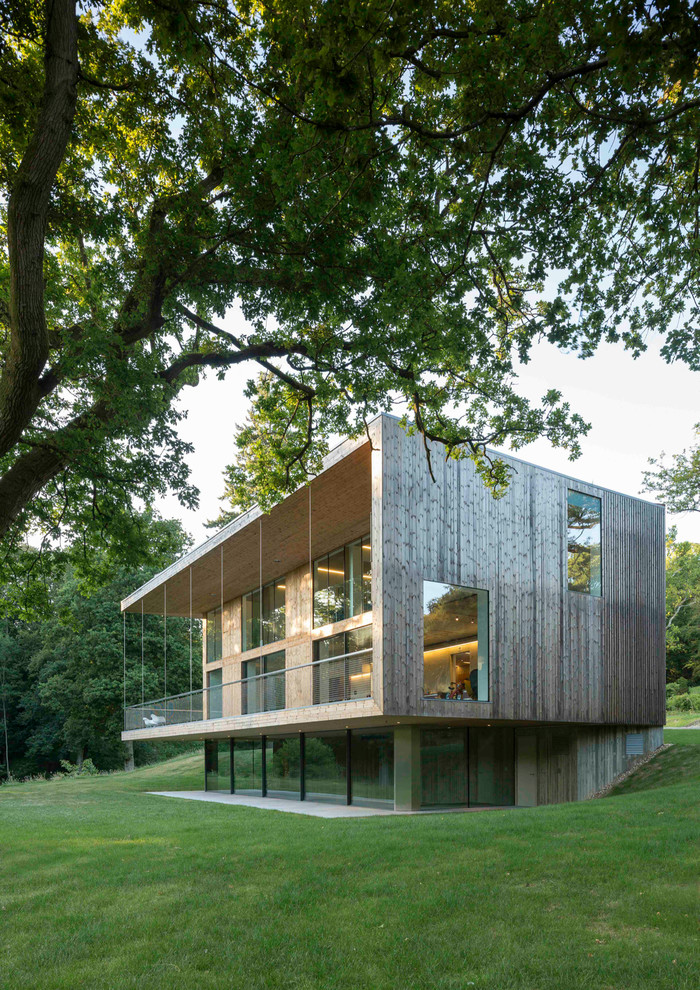 This is an example of a large contemporary three-storey brown exterior in London with wood siding and a flat roof.