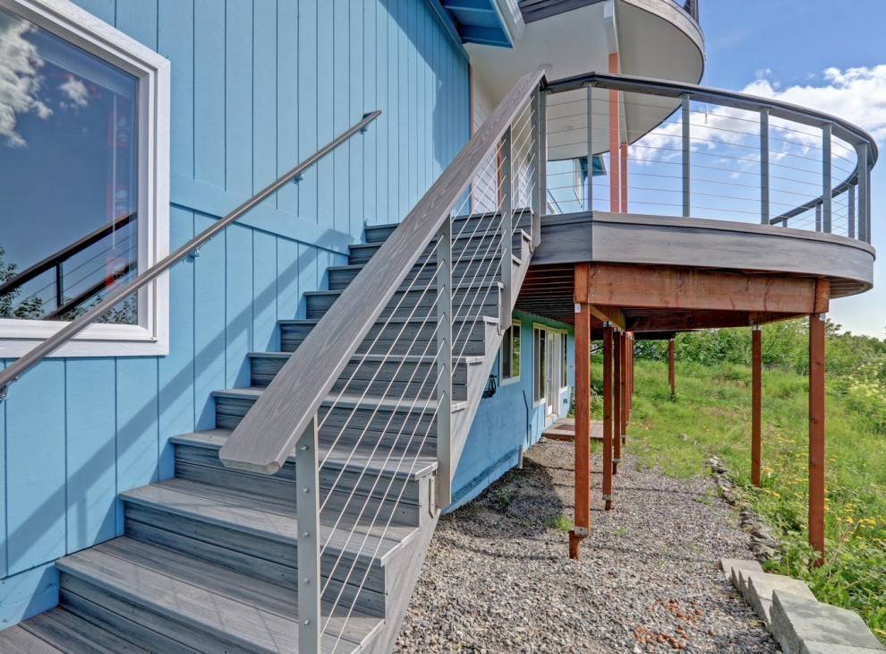 Inspiration for a large side yard ground level cable railing deck remodel with no cover