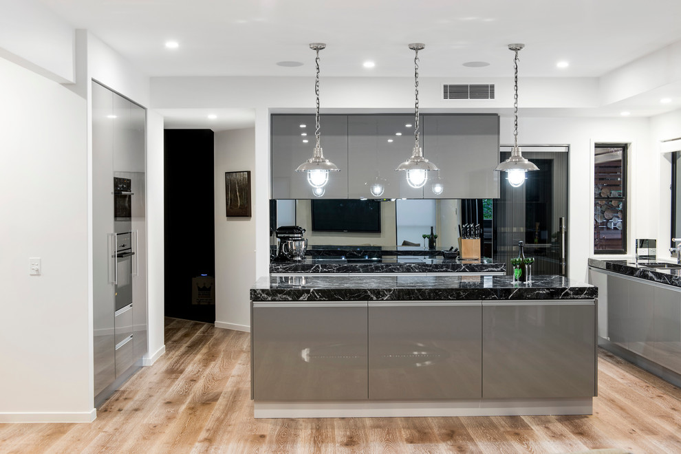 Photo of a contemporary kitchen in Brisbane with flat-panel cabinets, grey cabinets, marble benchtops and mirror splashback.