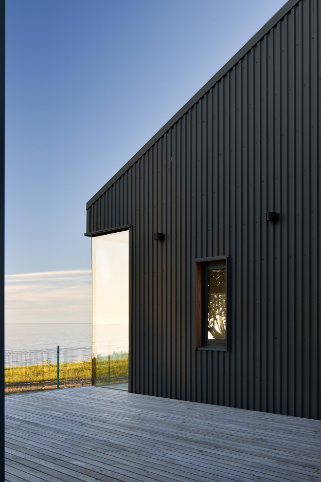 Стильный дизайн: одноэтажный, серый частный загородный дом в скандинавском стиле с облицовкой из металла и серой крышей - последний тренд