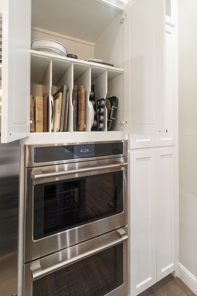 Example of a large transitional l-shaped medium tone wood floor and brown floor open concept kitchen design in Dallas with a farmhouse sink, shaker cabinets, white cabinets, quartz countertops, white backsplash, mosaic tile backsplash, stainless steel appliances, an island and white countertops