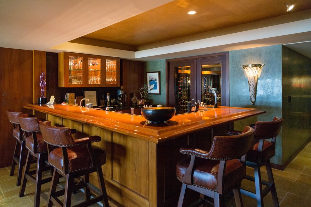Mid-sized modern l-shaped seated home bar in Denver with an undermount sink, glass-front cabinets, medium wood cabinets, wood benchtops, brown splashback, timber splashback, porcelain floors and beige floor.