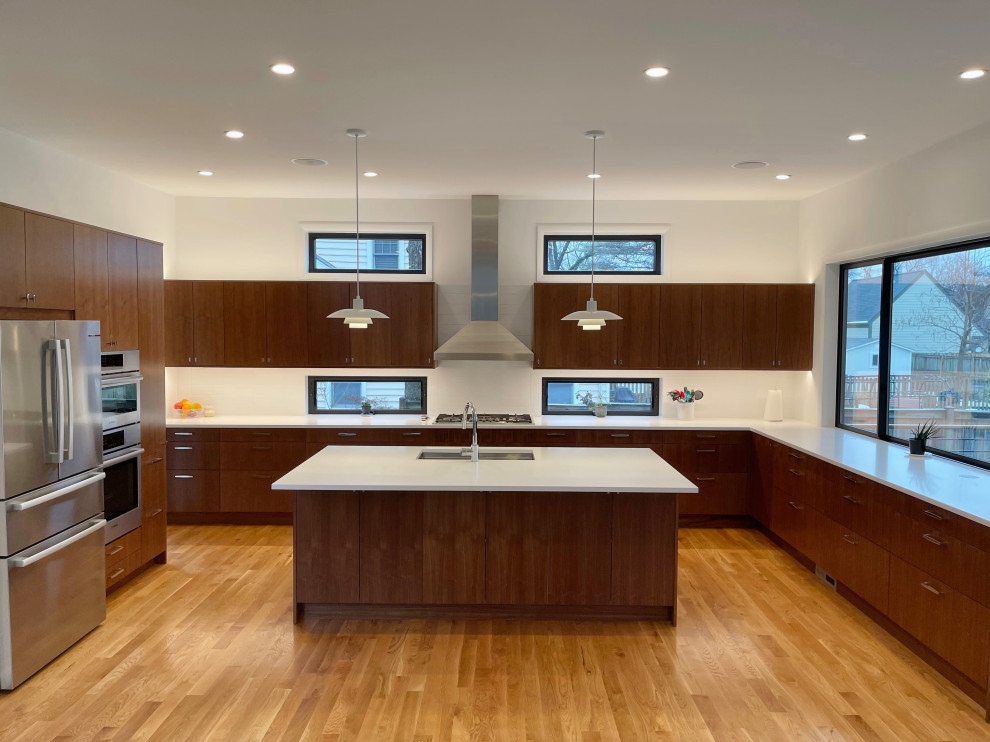 This is an example of a large midcentury kitchen in Seattle with an undermount sink, flat-panel cabinets, medium wood cabinets, ceramic splashback, stainless steel appliances, medium hardwood floors, with island and white benchtop.