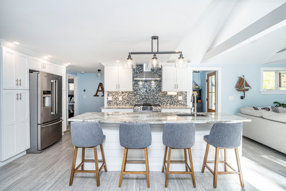 Photo of a mid-sized beach style kitchen in Boston with an undermount sink, shaker cabinets, white cabinets, quartzite benchtops, blue splashback, glass tile splashback, stainless steel appliances, porcelain floors, with island, grey floor, multi-coloured benchtop and vaulted.