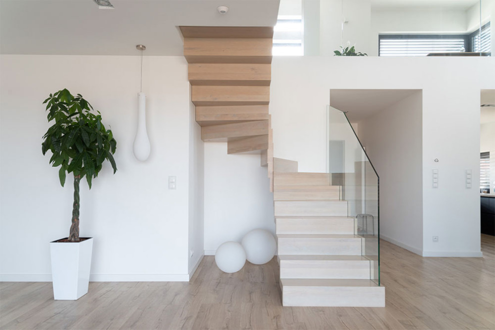 Cette photo montre un escalier courbe moderne avec des marches en verre, des contremarches en bois et un garde-corps en verre.