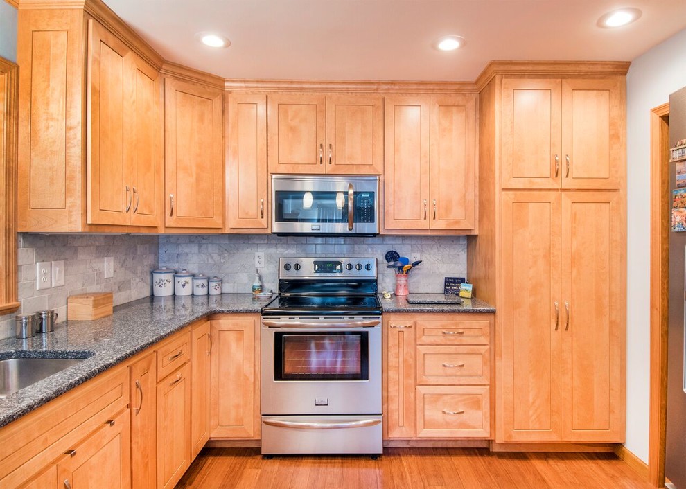 Mid-sized transitional u-shaped bamboo floor and brown floor enclosed kitchen photo in Cincinnati with a double-bowl sink, shaker cabinets, light wood cabinets, granite countertops, gray backsplash, marble backsplash, stainless steel appliances, a peninsula and gray countertops