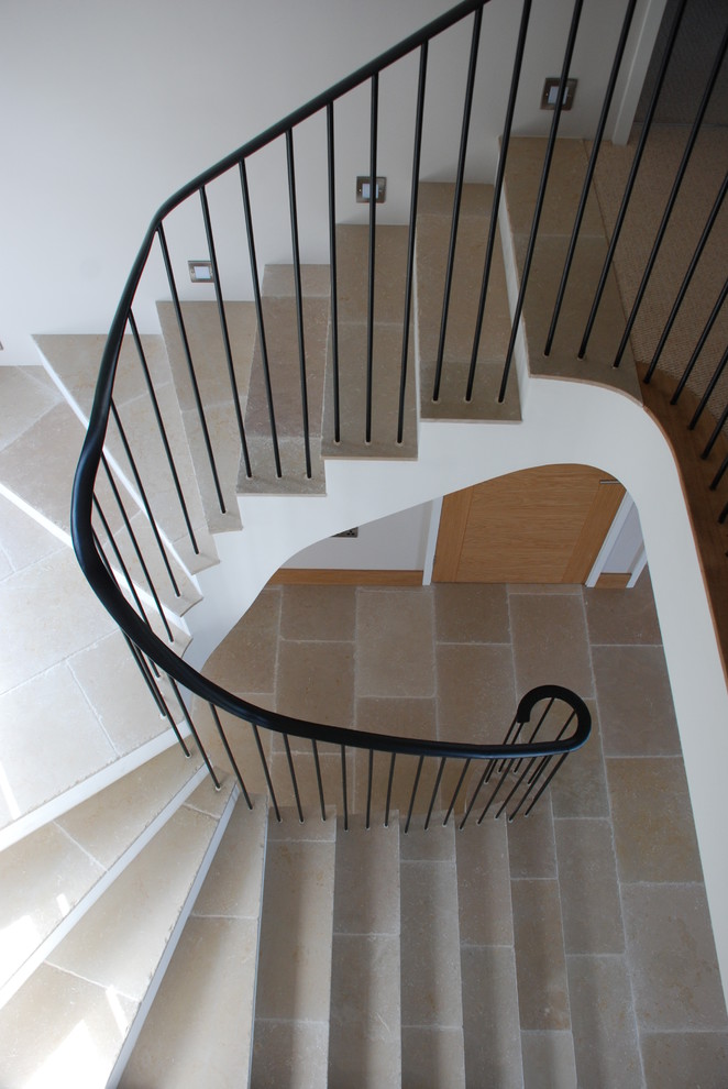 Contemporary limestone spiral staircase in Cornwall with limestone risers and metal railing.