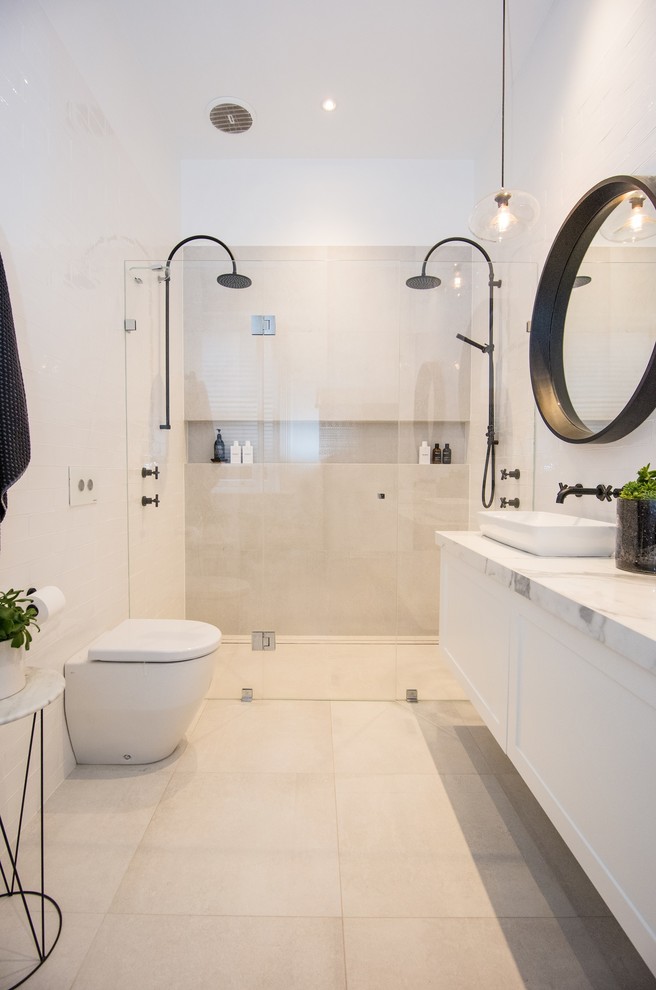 Photo of a mid-sized contemporary master bathroom in Adelaide with recessed-panel cabinets, white cabinets, a double shower, a wall-mount toilet, white tile, porcelain tile, white walls, porcelain floors, a vessel sink, solid surface benchtops, white floor and a hinged shower door.