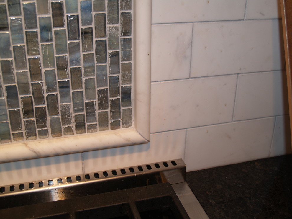 Example of a transitional kitchen design in Milwaukee with white backsplash, stone tile backsplash, stainless steel appliances and two islands