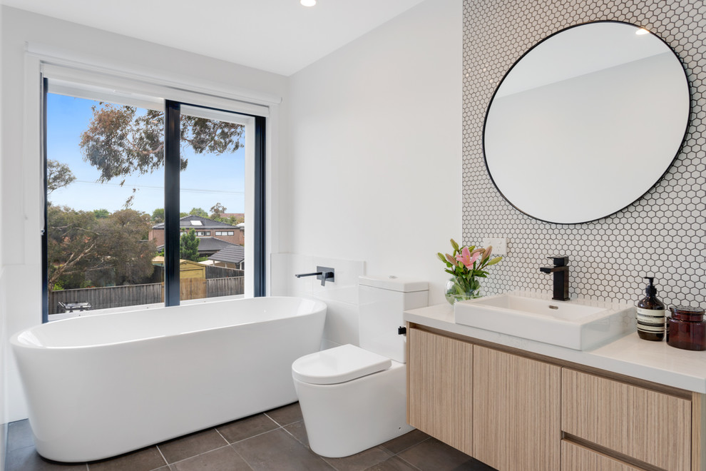 Inspiration for a mid-sized contemporary master bathroom in Melbourne with raised-panel cabinets, light wood cabinets, a freestanding tub, a one-piece toilet, ceramic tile, white walls, ceramic floors, a drop-in sink, marble benchtops, brown floor and white benchtops.