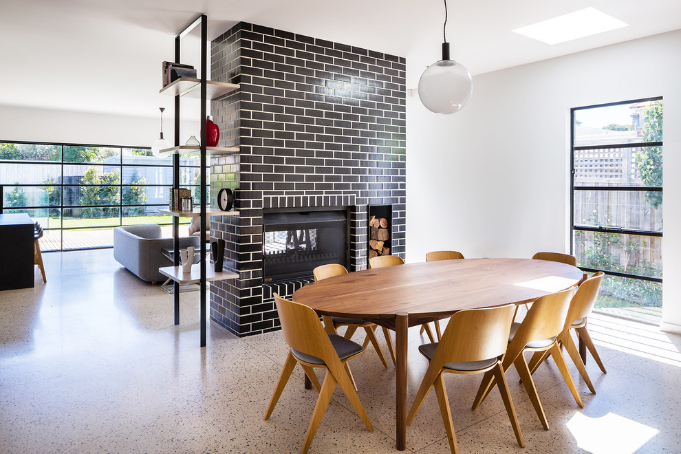 Contemporary open plan dining in Melbourne with white walls, concrete floors, a two-sided fireplace, a brick fireplace surround and beige floor.