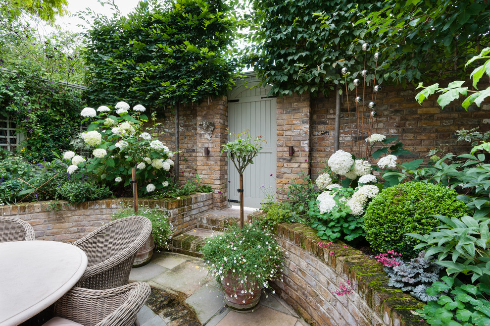 Small traditional courtyard patio in London with brick pavers.