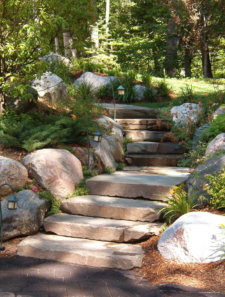 Traditional sloped garden in Other with natural stone pavers.