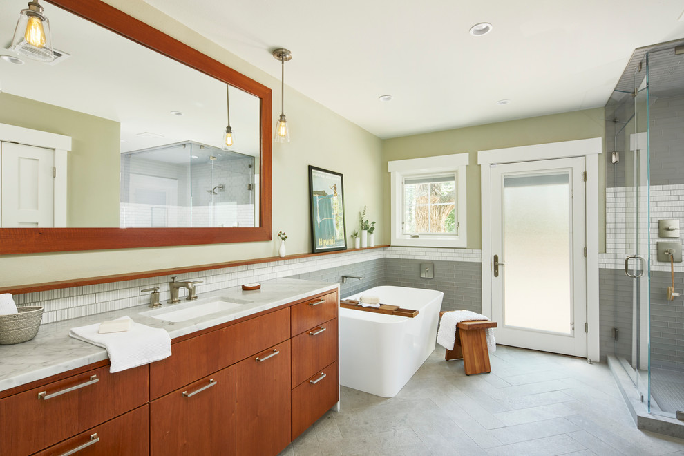 Design ideas for a small country master bathroom in Austin with flat-panel cabinets, medium wood cabinets, a freestanding tub, an open shower, a one-piece toilet, gray tile, glass tile, grey walls, limestone floors, a drop-in sink, marble benchtops, grey floor, a hinged shower door and grey benchtops.