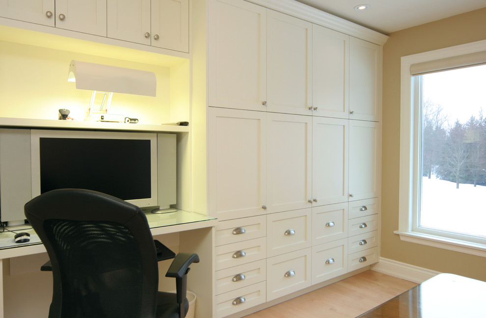 Photo of a mid-sized contemporary home office in Toronto with beige walls, light hardwood floors and a built-in desk.