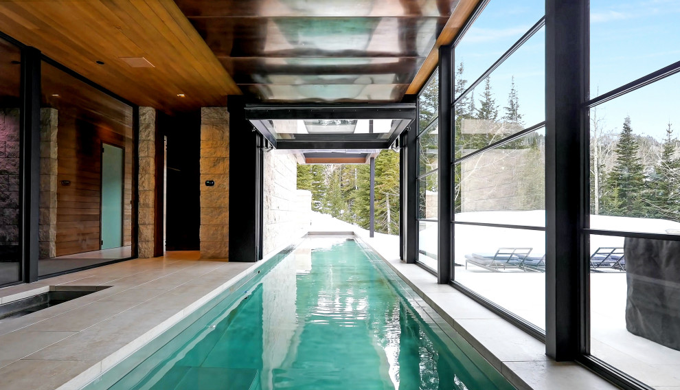 Foto de piscina alargada minimalista extra grande interior y rectangular con adoquines de piedra natural