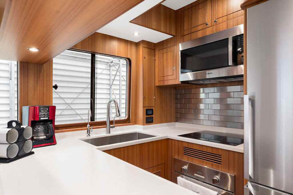 Inspiration for a modern eat-in kitchen in Miami with medium wood cabinets, metallic splashback, metal splashback, stainless steel appliances, medium hardwood floors and white benchtop.