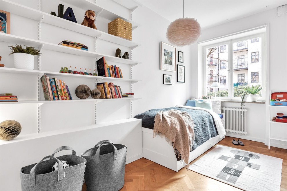 Photo of a scandinavian kids' bedroom for kids 4-10 years old and boys in Stockholm with white walls, medium hardwood floors and brown floor.