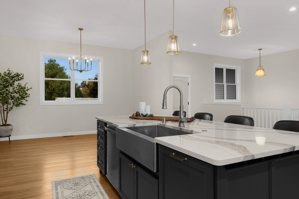 Inspiration for a large transitional l-shaped light wood floor and brown floor eat-in kitchen remodel with a farmhouse sink, flat-panel cabinets, gray cabinets, white backsplash, ceramic backsplash, stainless steel appliances, an island, white countertops and quartz countertops