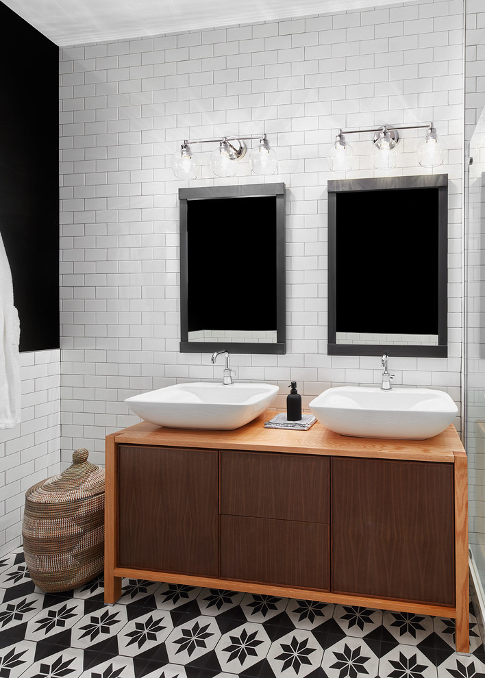 Photo of a mid-sized modern master bathroom in Chicago with light wood cabinets, a one-piece toilet, white tile, subway tile, black walls, mosaic tile floors, a vessel sink, wood benchtops, black floor, brown benchtops, a double vanity and a freestanding vanity.