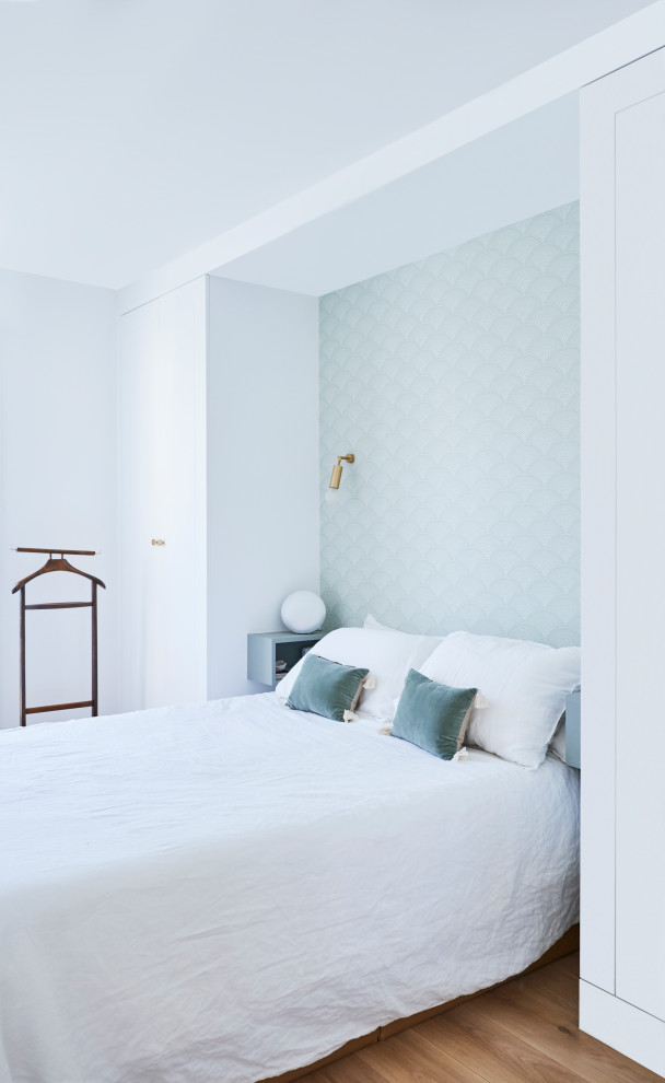 Idée de décoration pour une petite chambre parentale nordique avec un mur blanc, un sol en bois brun, un sol beige, du papier peint et dressing.