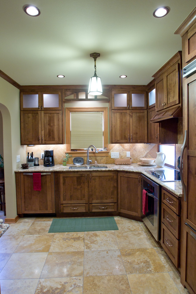 This is an example of a mid-sized arts and crafts l-shaped eat-in kitchen in Other with a double-bowl sink, shaker cabinets, dark wood cabinets, granite benchtops, beige splashback, stainless steel appliances, a peninsula, beige floor and limestone floors.
