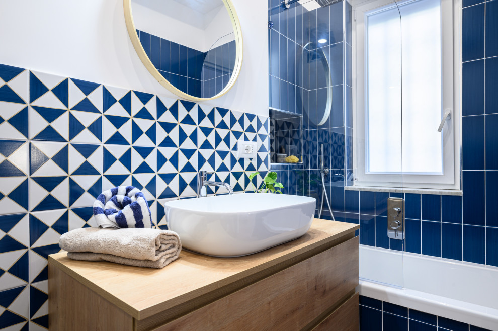 Cette photo montre une salle de bain principale méditerranéenne avec un placard à porte plane, des portes de placard bleues, une baignoire posée, WC séparés, un carrelage bleu, des carreaux de céramique, un mur blanc, une vasque, un plan de toilette en bois, meuble simple vasque et meuble-lavabo suspendu.