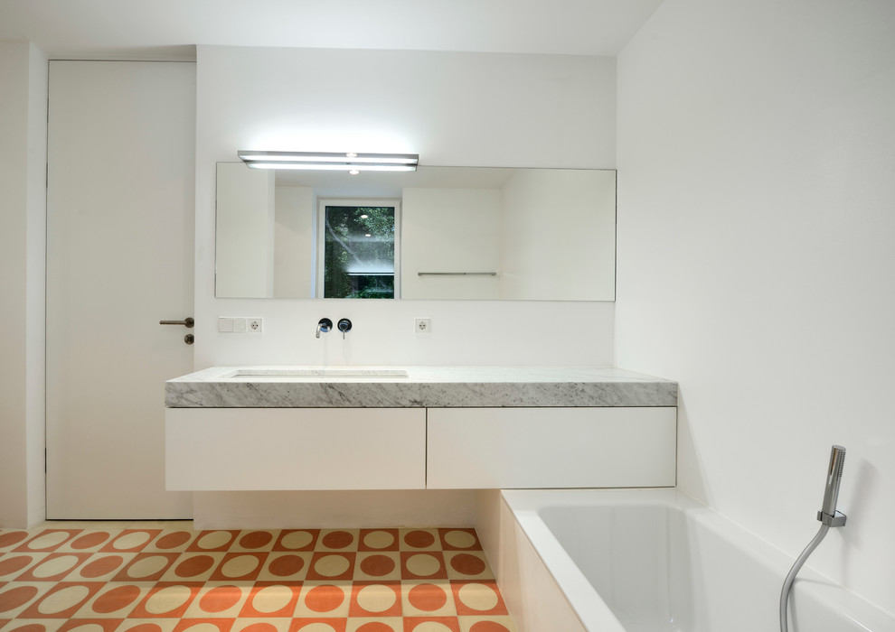 This is an example of a medium sized contemporary ensuite bathroom in Munich with white cabinets, a built-in bath, white walls, a submerged sink, flat-panel cabinets, orange tiles, white tiles, cement tiles and marble worktops.