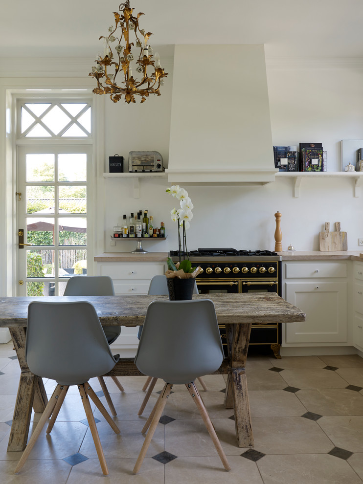 Design ideas for a small traditional u-shaped eat-in kitchen in Copenhagen with a drop-in sink, white cabinets, white splashback, black appliances, limestone floors, no island, recessed-panel cabinets and limestone benchtops.