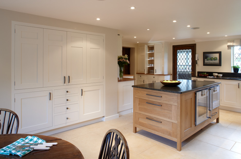 Design ideas for a large traditional l-shaped eat-in kitchen in Surrey with shaker cabinets, light wood cabinets, granite benchtops, black splashback, stainless steel appliances, limestone floors and with island.
