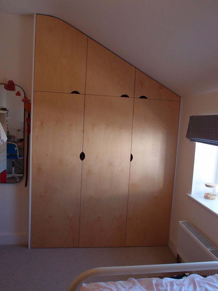 Cette photo montre une très grande armoire encastrée scandinave en bois clair avec un placard à porte plane, moquette et un sol gris.