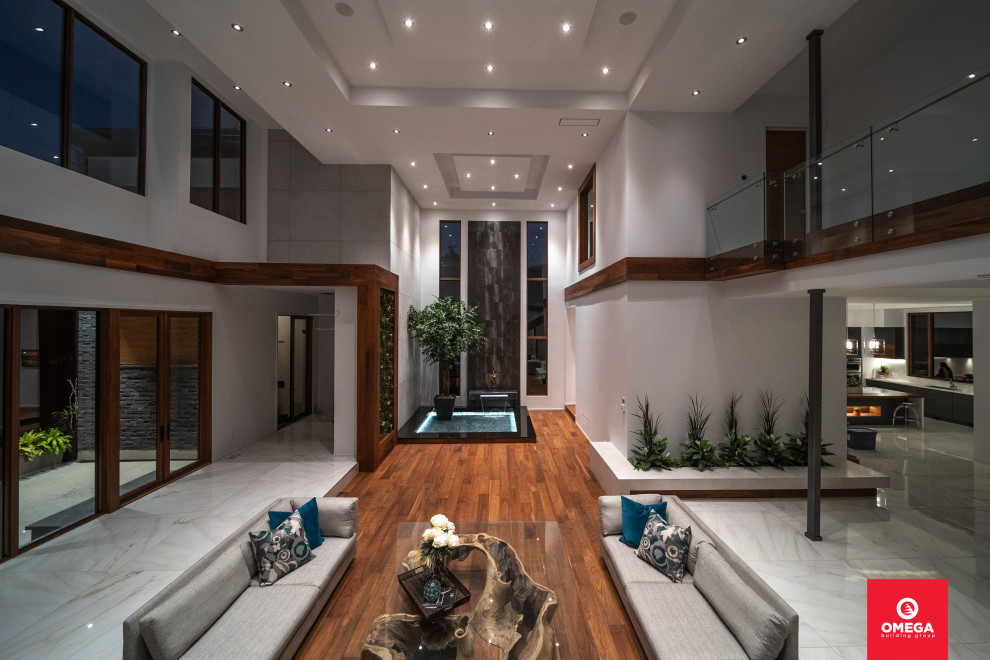 This is an example of an expansive modern foyer in Toronto with white walls, ceramic floors, a double front door, a medium wood front door, white floor and coffered.