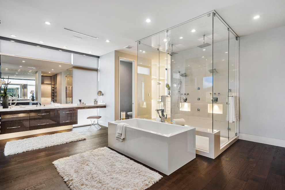 Large trendy master white tile brown floor and dark wood floor freestanding bathtub photo in Miami with flat-panel cabinets, dark wood cabinets, onyx countertops, a hinged shower door, white countertops and gray walls