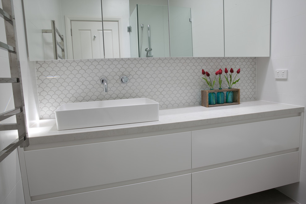 This is an example of a mid-sized modern kids bathroom in Sydney with flat-panel cabinets, white cabinets, a one-piece toilet, white tile, ceramic tile, white walls, porcelain floors, a pedestal sink and engineered quartz benchtops.