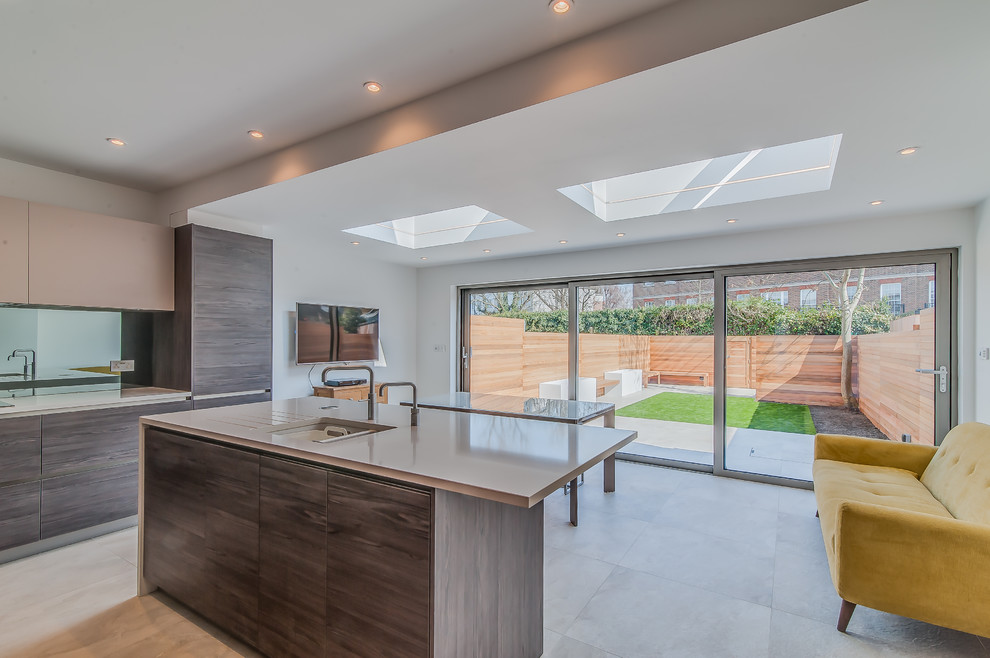 This is an example of a small contemporary l-shaped eat-in kitchen in Surrey with an undermount sink, flat-panel cabinets, medium wood cabinets, solid surface benchtops, metallic splashback, mirror splashback, stainless steel appliances, porcelain floors and with island.