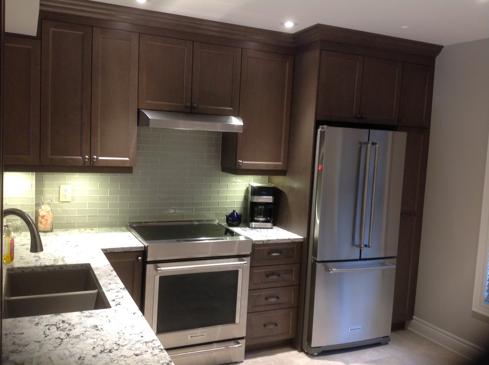 Kitchen - small transitional l-shaped porcelain tile and beige floor kitchen idea in Toronto with an undermount sink, recessed-panel cabinets, dark wood cabinets, granite countertops, gray backsplash, glass tile backsplash, paneled appliances, no island and multicolored countertops