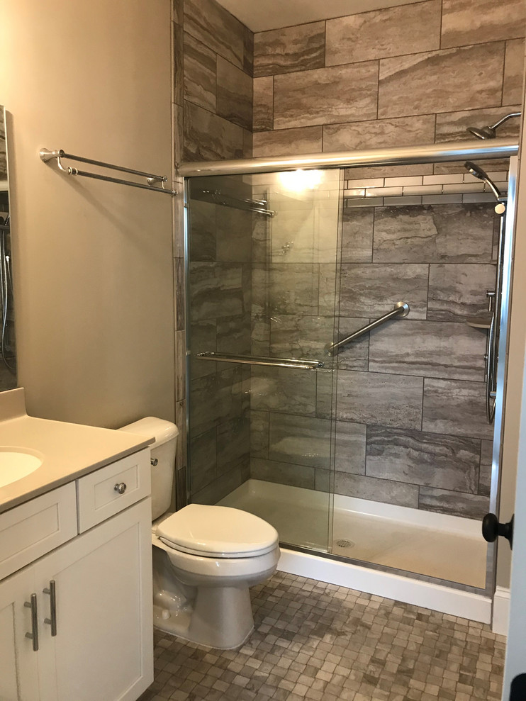 Design ideas for a large arts and crafts master bathroom in New York with recessed-panel cabinets, white cabinets, an alcove shower, a one-piece toilet, grey walls, ceramic floors, an undermount sink, multi-coloured floor, a sliding shower screen, beige benchtops, gray tile and ceramic tile.