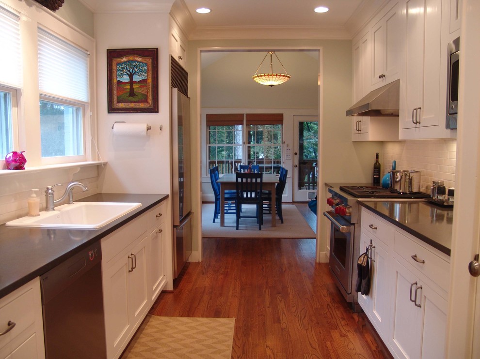Photo of a traditional galley separate kitchen in Atlanta with stainless steel appliances, a drop-in sink, shaker cabinets, white cabinets, white splashback and subway tile splashback.