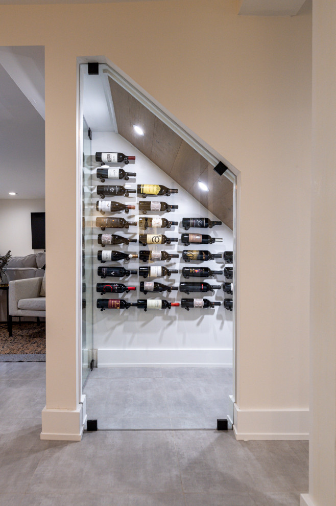This is an example of a large modern look-out basement in Philadelphia with a home bar, white walls and grey floors.