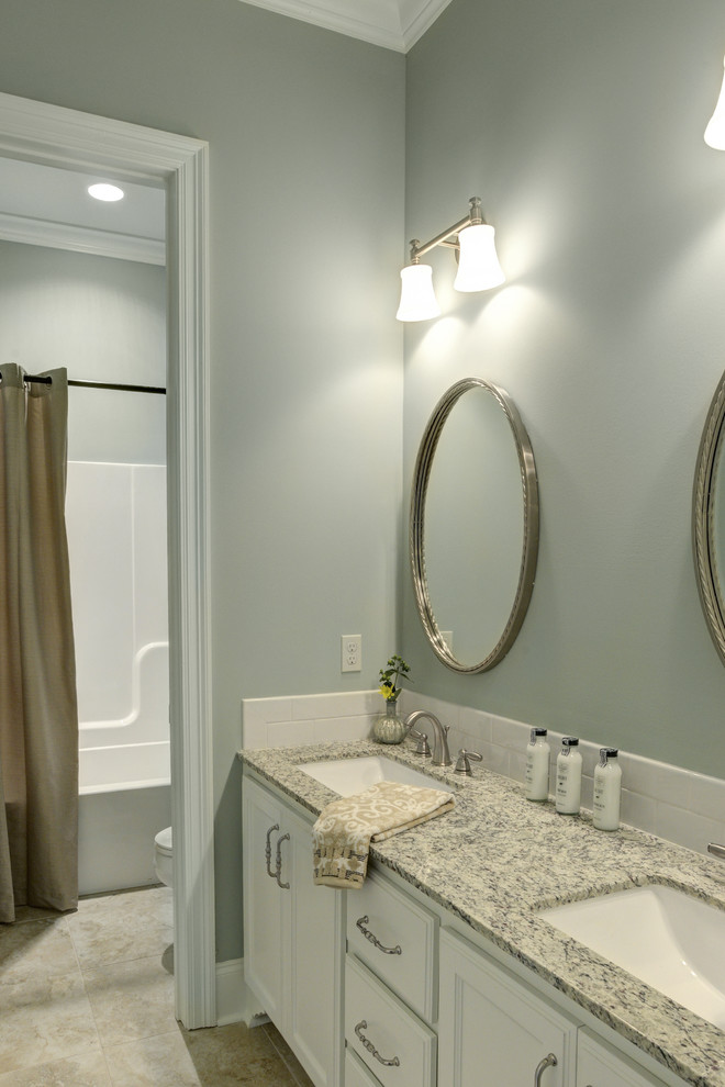 Inspiration for a mid-sized transitional kids bathroom in New Orleans with an undermount sink, recessed-panel cabinets, white cabinets, granite benchtops, a shower/bathtub combo, white tile, subway tile, grey walls, ceramic floors, beige floor, white benchtops and a two-piece toilet.