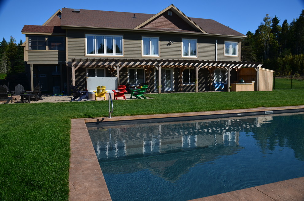 Pool - large rustic backyard stamped concrete and rectangular pool idea