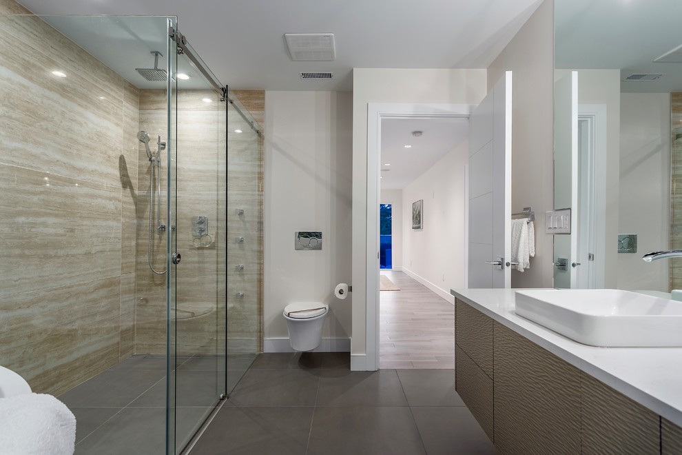 Design ideas for a large contemporary master bathroom in Vancouver with flat-panel cabinets, grey cabinets, a freestanding tub, a corner shower, a wall-mount toilet, beige tile, stone tile, beige walls, cement tiles, a drop-in sink, quartzite benchtops, grey floor and a sliding shower screen.