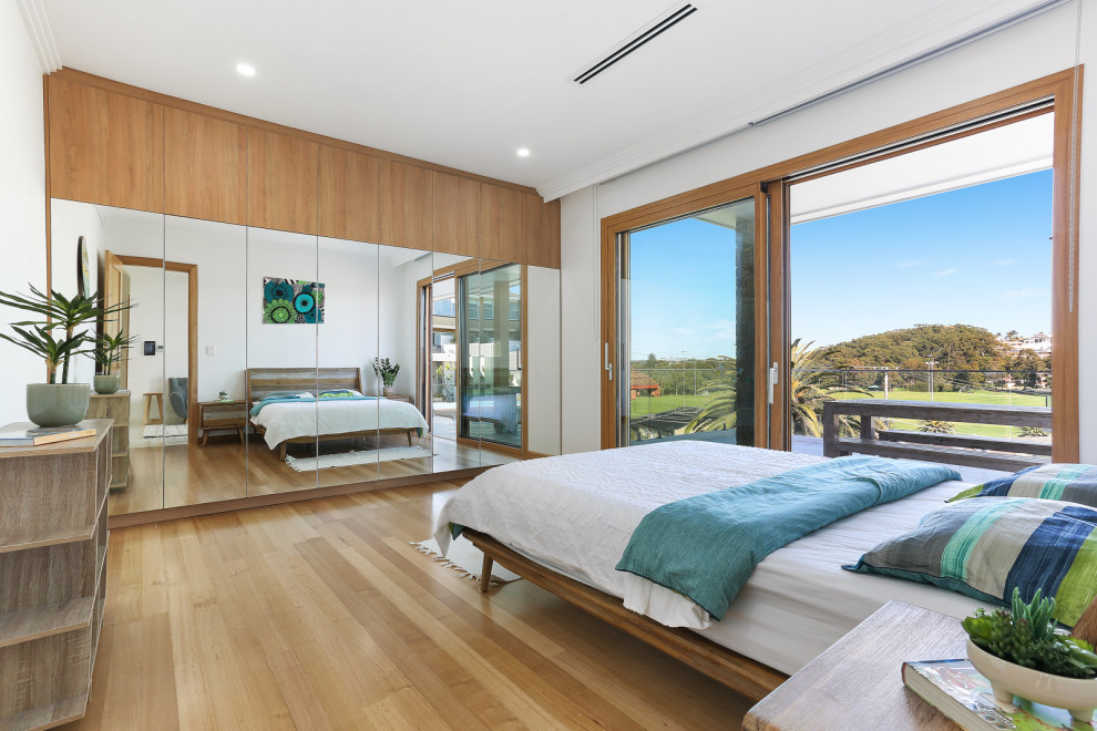 Inspiration for a contemporary bedroom in Sydney with white walls, medium hardwood floors and brown floor.
