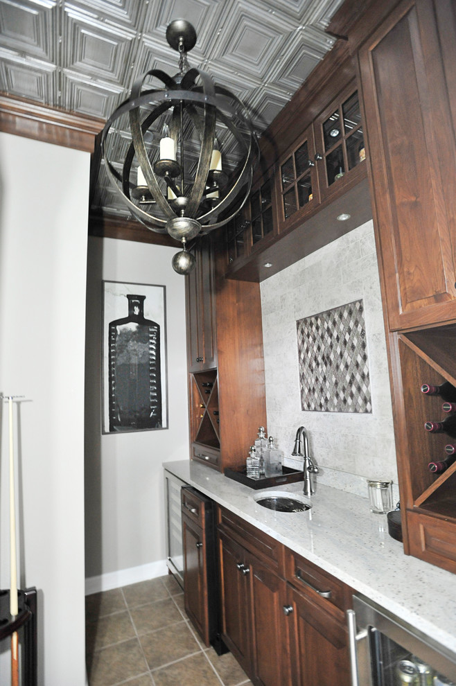 Mid-sized country single-wall wet bar in Chicago with an undermount sink, dark wood cabinets, quartzite benchtops, ceramic floors, brown floor and white benchtop.
