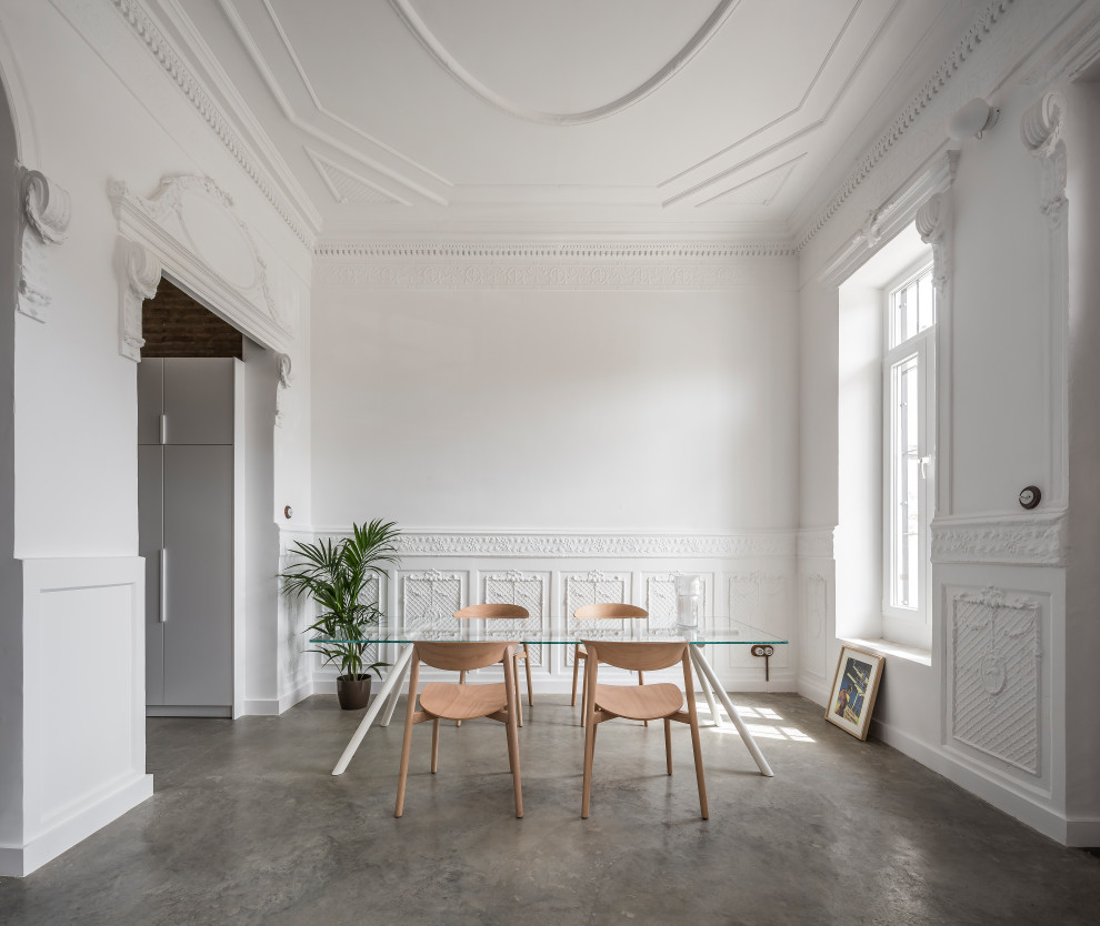 На фото: столовая в современном стиле с белыми стенами, бетонным полом, серым полом и панелями на стенах с