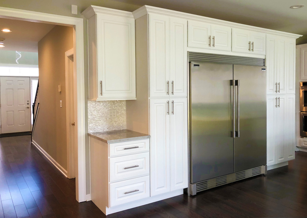 This is an example of a large traditional u-shaped kitchen in Baltimore with an undermount sink, raised-panel cabinets, white cabinets, quartzite benchtops, grey splashback, ceramic splashback, stainless steel appliances, laminate floors, with island, brown floor and yellow benchtop.