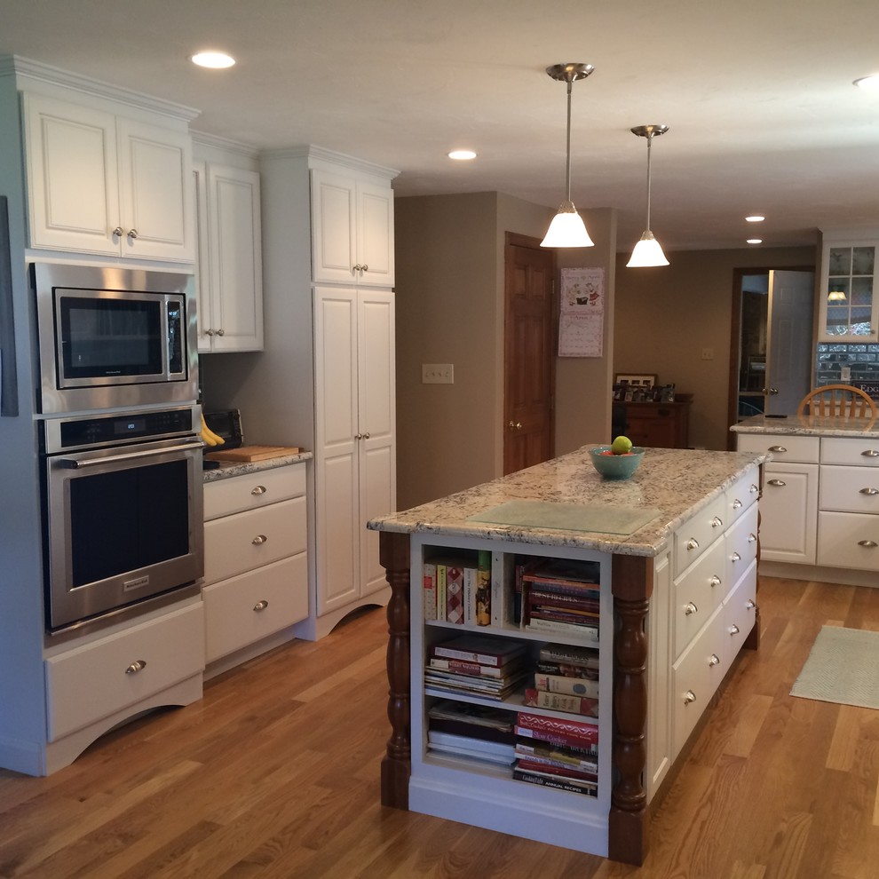 Inspiration for a transitional u-shaped medium tone wood floor eat-in kitchen remodel in Boston with an undermount sink, raised-panel cabinets, white cabinets, granite countertops, blue backsplash, glass tile backsplash, stainless steel appliances and an island