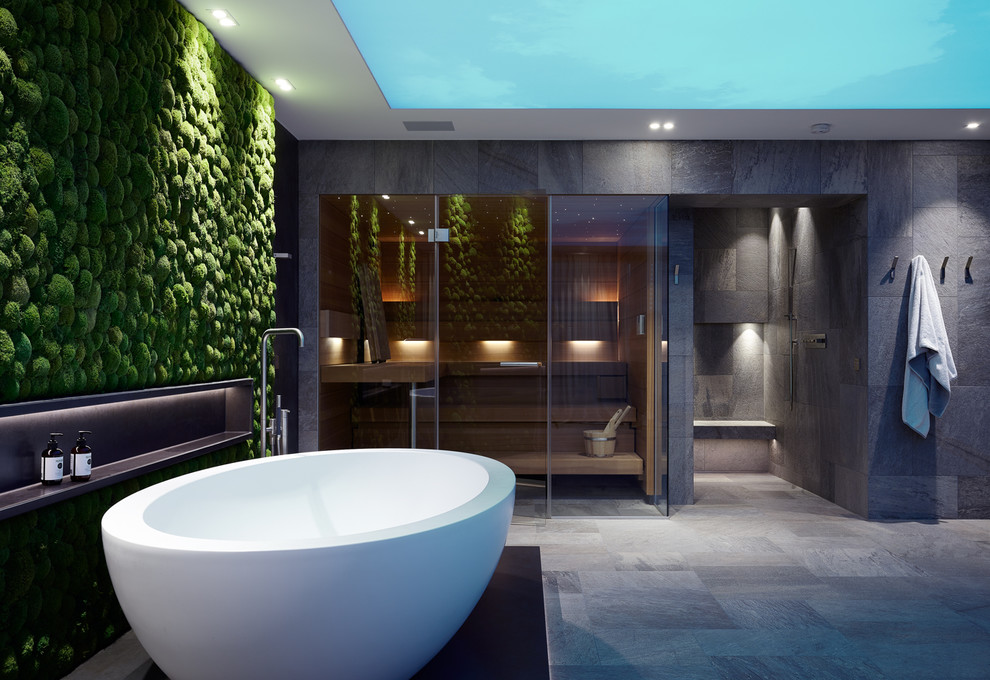 Large contemporary bathroom in Cologne with flat-panel cabinets, dark wood cabinets, a freestanding tub, a curbless shower, a two-piece toilet, gray tile, ceramic tile, black walls, ceramic floors, with a sauna, a trough sink, grey floor, an open shower and black benchtops.