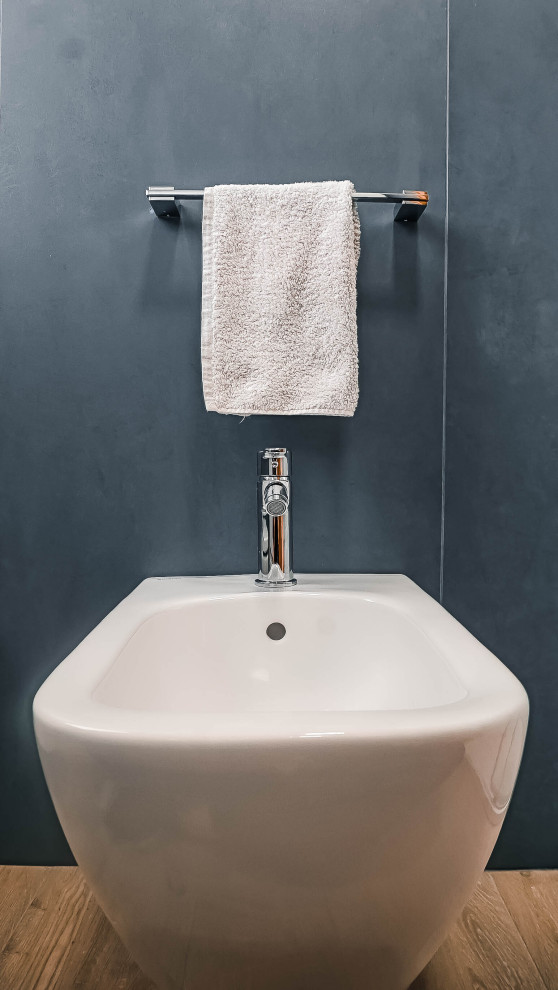 Immagine di un bagno di servizio industriale di medie dimensioni con WC a due pezzi, piastrelle blu, piastrelle in gres porcellanato, pareti bianche, pavimento con piastrelle effetto legno e pavimento marrone