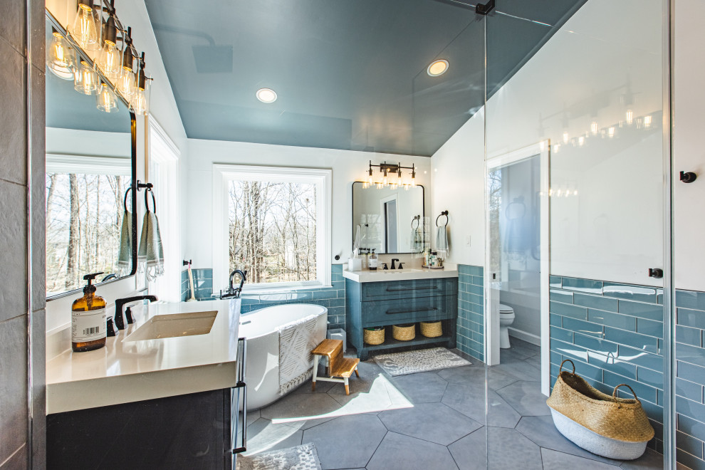 Photo of a medium sized modern ensuite bathroom in DC Metro with blue cabinets, a freestanding bath, a corner shower, blue tiles, metro tiles, blue walls, engineered stone worktops, brown floors, a sliding door and a single sink.